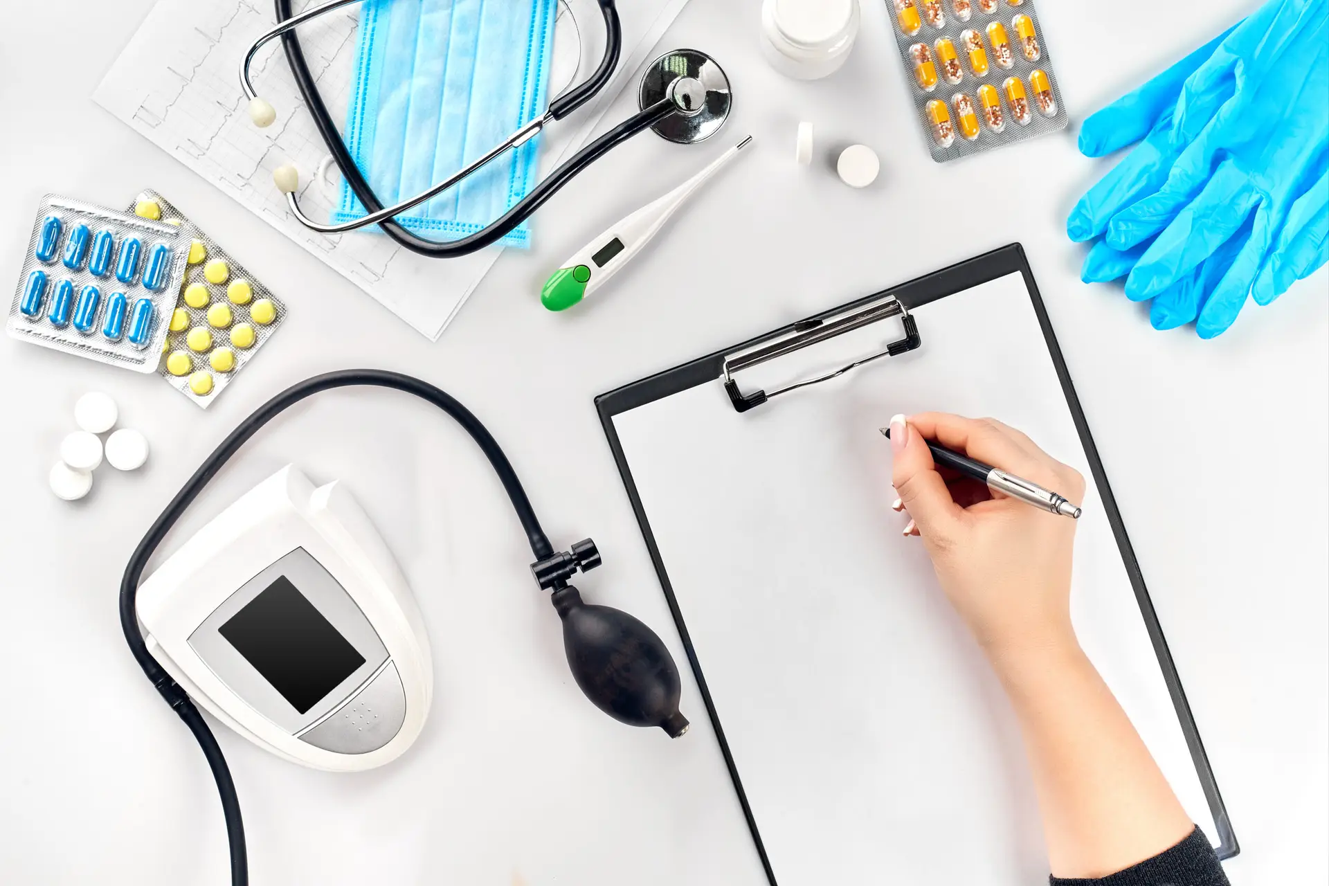 Female doctor's hand filling the medical record on white table