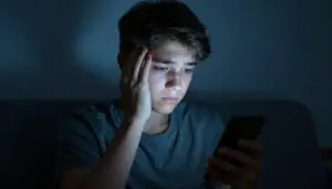 Teen looking distressed while looking at smartphone, illustrating cyberbullying and tech trauma
