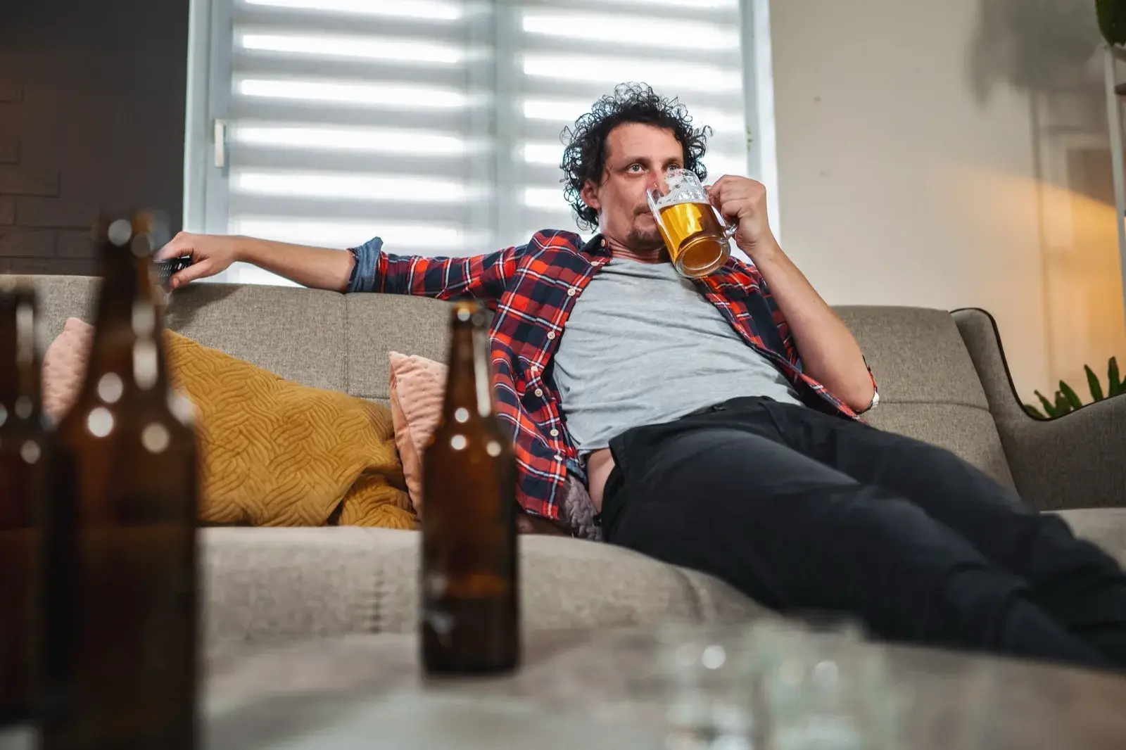 Man drinking beer alone at home on the sofa