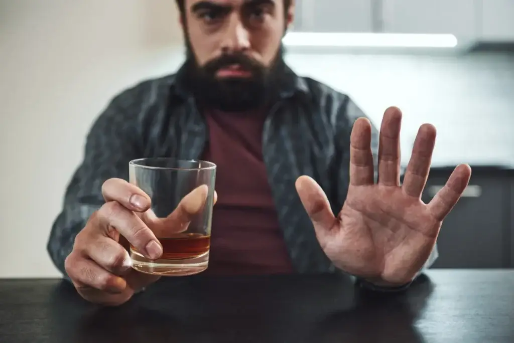 Man refusing a glass of alcohol, choosing sobriety