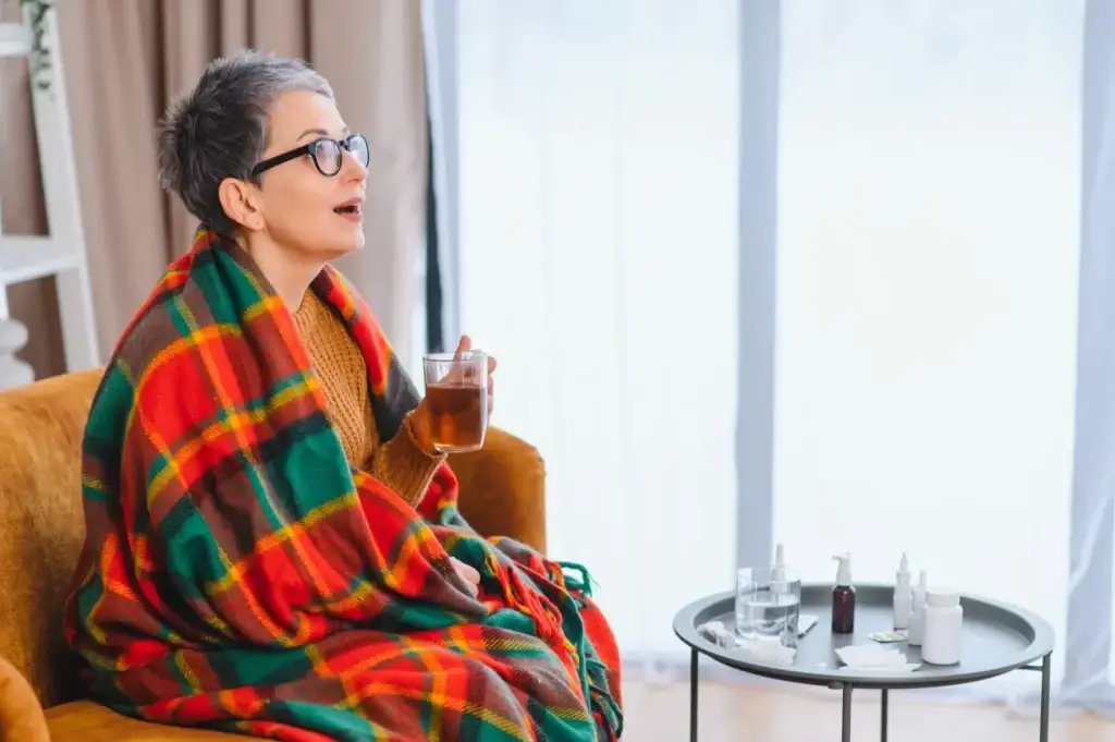 Woman recovering on the sofa with tea and medicine