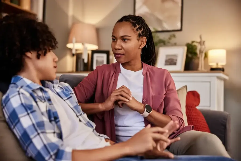 A parent having a calm, supportive conversation with their teenager about substance use.