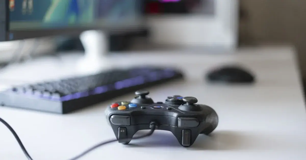A game controller on a desk beside a keyboard in daylight.