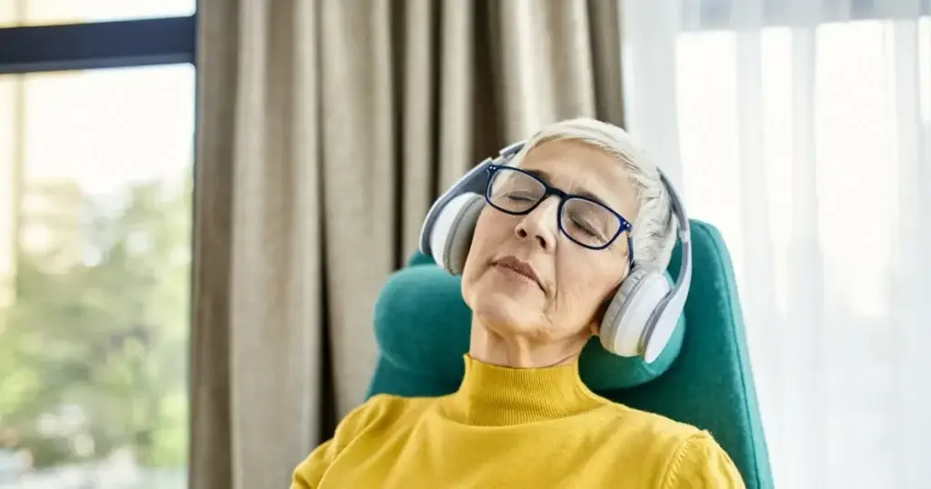 Guided Imagery in Recovery: What It Does and What It Doesn't 8 A woman resting in an armchair beside a window with her eyes closed, listening through headphones.
